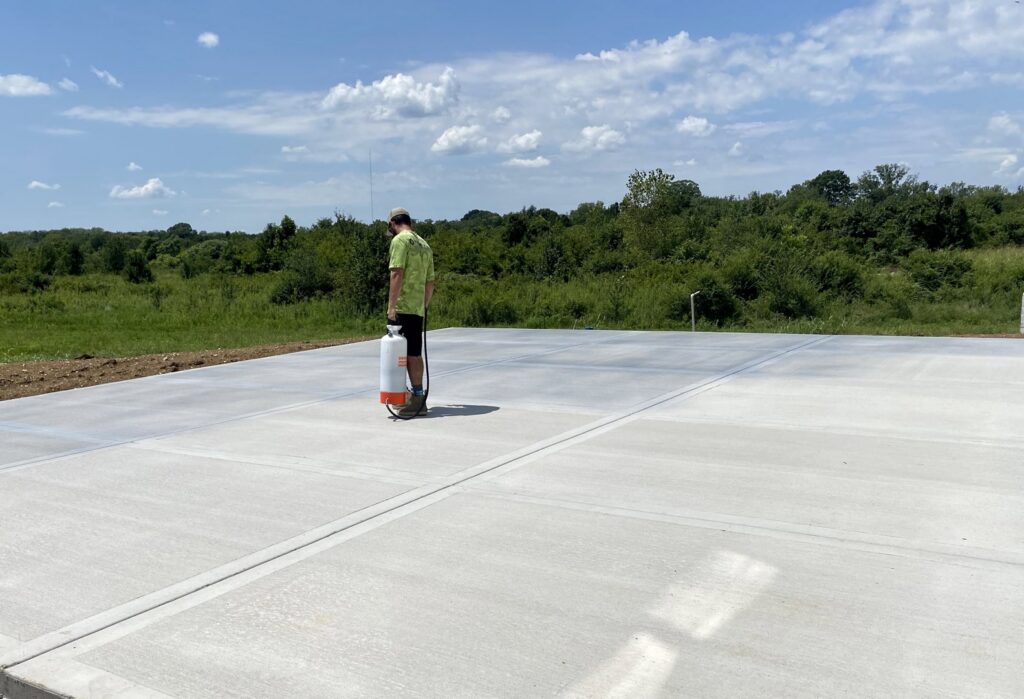 A Waterly, Co. Power Washing technician applying a concrete treatment with a sprayer in Nashville, TN.