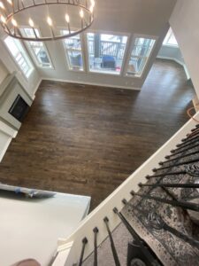 A hallway with newly finished dark hardwood floors, showing a roller used for applying finish by IHS flooring LLC in Brighton, CO.