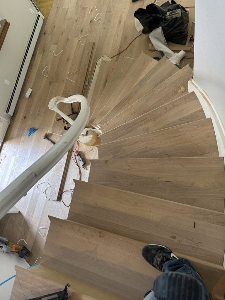 A kitchen area with a newly finished hardwood floor, showing a roller used for applying finish by IHS flooring LLC in Brighton, CO.