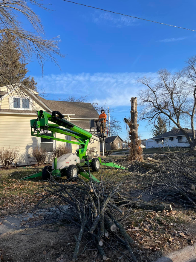 An arborist from Mr Spruce Tree Service LLC performing tree stump removal with a spider lift in Ankeny, IA.