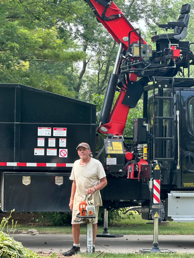 An arborist holding a chainsaw in front of a tree service truck at Arborist Care Tree Service in Columbus, OH.