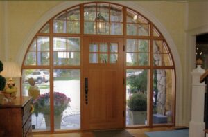 A grand arched entryway with a custom wooden door and large windows installed by Connaughton Construction in Waltham, MA