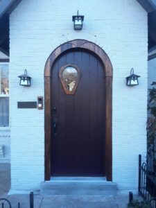 A newly installed dark arched front door with a distinctive window, enhancing the exterior of a home by Huff Consolidated Enterprises LLC in Clarksville, TN.