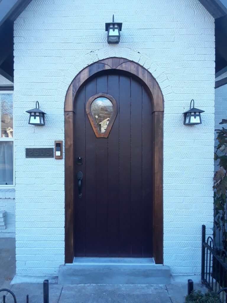 A newly installed dark arched front door with a distinctive window, enhancing the exterior of a home by Huff Consolidated Enterprises LLC in Clarksville, TN.