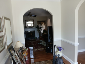 An elegant arched interior doorway leading to a living room with a fireplace, completed by Quiros Remodeling in Greenville, SC.