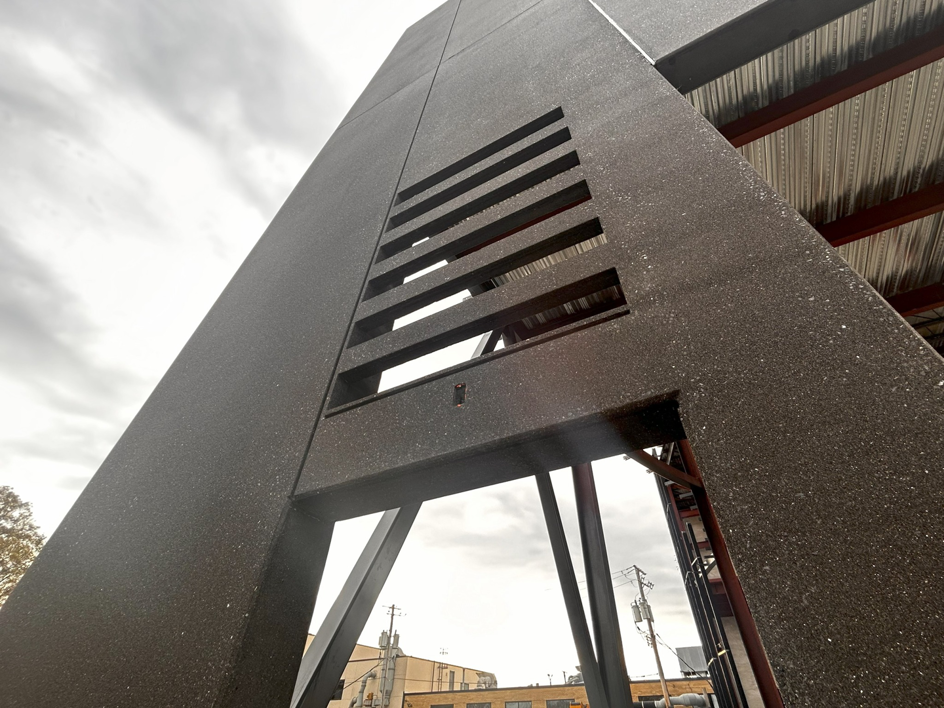 A close-up view of a dark, textured architectural precast panel forming part of a building structure by Lombard Architectural Precast Products Company in Aurora, IL.