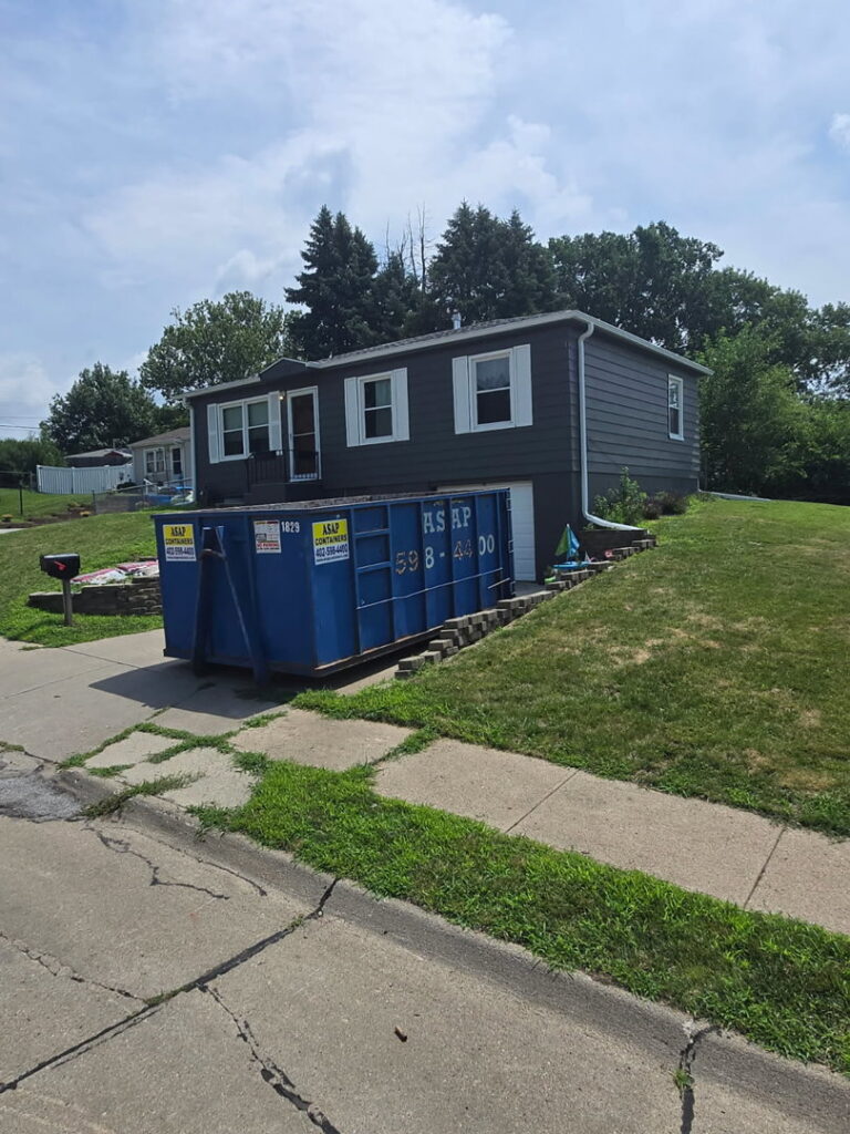 An ASAP Containers inc. blue dumpster placed in front of a residential home for junk removal in Omaha, NE.