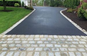 A newly paved asphalt driveway with a decorative cobblestone border by Mincho Contractor LLC in Jersey City, NJ
