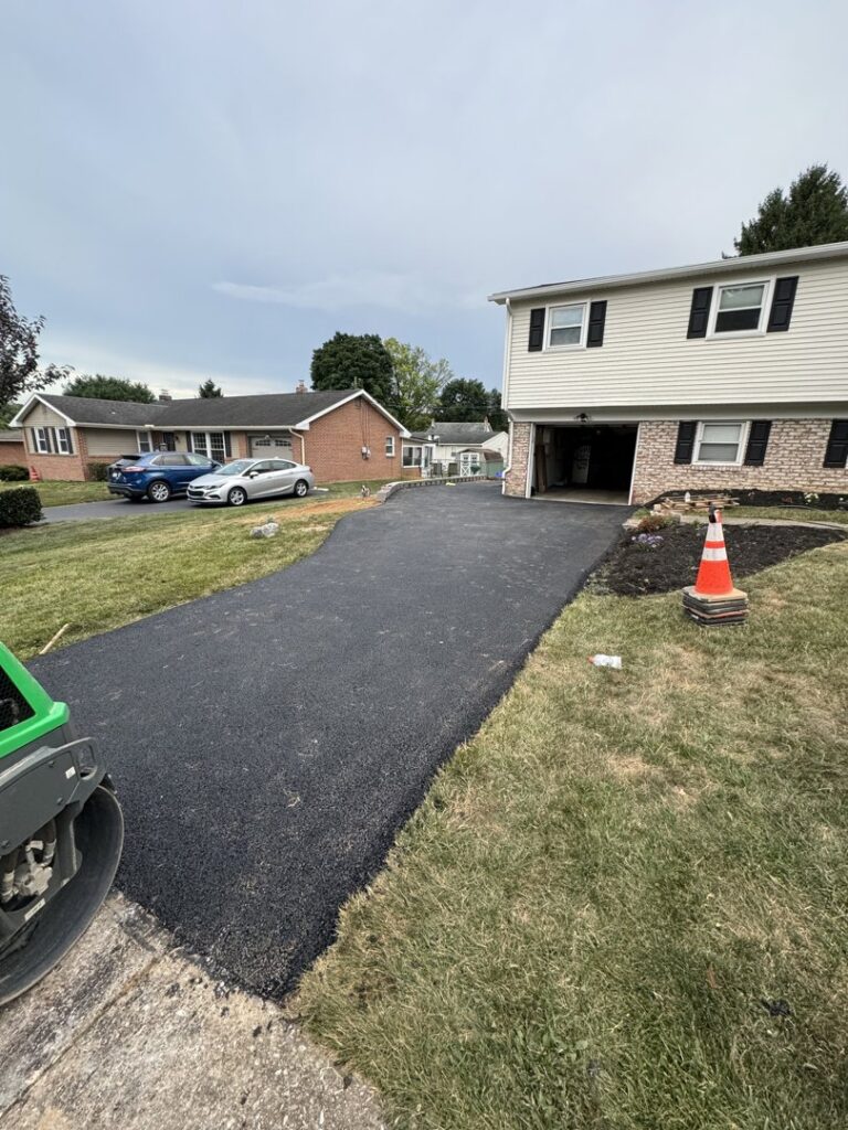 Asphalt driveway installation in progress with a roller, by Angeles Contractors LLC in New Oxford, PA.