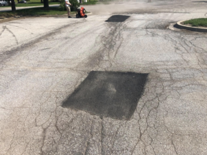A worker performing asphalt patching and sealcoating at Gorman sealcoating & striping in Blue Springs, MO.