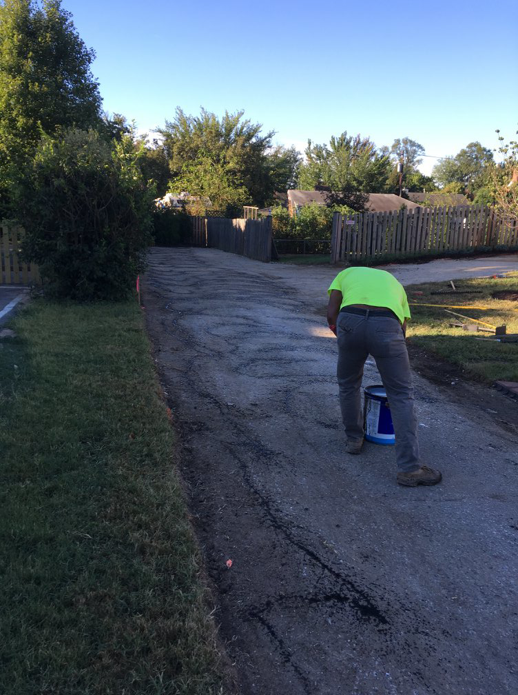 A worker performing asphalt repair or sealcoating for Free State Contracting Company in Annapolis, MD