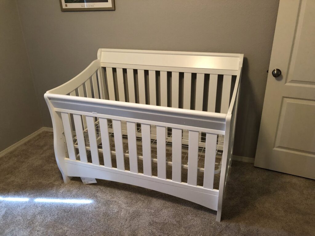 A newly assembled white baby crib standing in a nursery room, showcasing furniture assembly services by The ABQ Handyman in Albuquerque, NM.