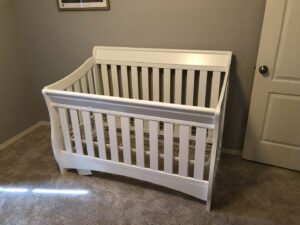 A newly assembled white baby crib standing in a nursery room, showcasing furniture assembly services by The ABQ Handyman in Albuquerque, NM.