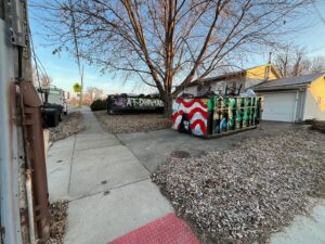 Two AT Disposal roll-off dumpsters filled with junk on a residential street in Dewitt, IA.