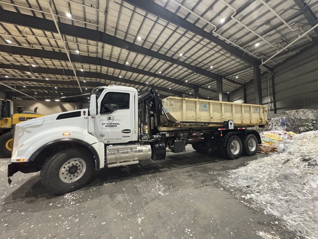 An AT Disposal roll-off truck inside a recycling facility, ready for material transport in Dewitt, IA.
