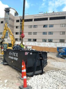 An ATEX Dumpsters Services roll-off dumpster filled with debris at a construction site in Austin, TX.