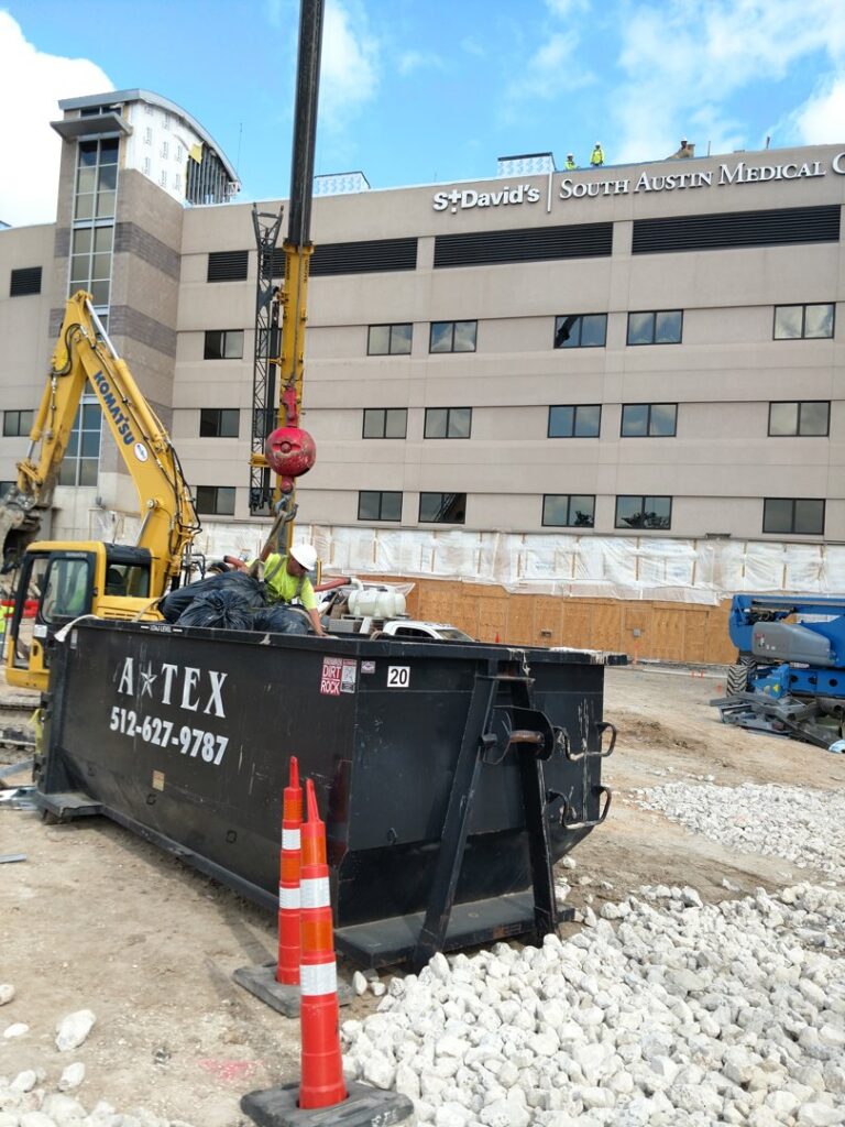 An ATEX Dumpsters Services roll-off dumpster filled with debris at a construction site in Austin, TX.