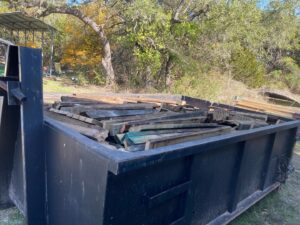 An ATEX Dumpsters Services roll-off dumpster filled with wood debris for junk removal in Austin, TX.