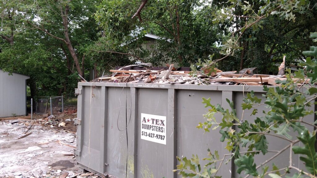 An ATEX Dumpsters Services roll-off dumpster filled with wood and construction debris in Austin, TX.