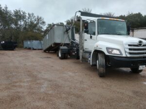 An ATEX Dumpsters Services truck operating a roll-off dumpster for junk removal in Austin, TX.