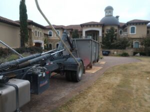 An ATEX Dumpsters Services truck placing a roll-off dumpster at a residential property in Austin, TX.