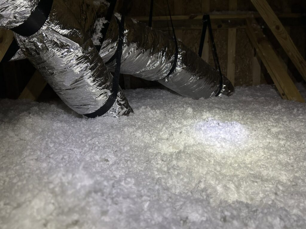 Close-up of blown-in insulation in an attic with visible ductwork by Insulation By Cohen's in Moncks Corner, SC.