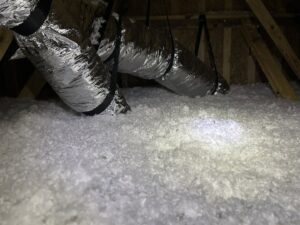 Close-up of blown-in insulation in an attic with visible ductwork by Insulation By Cohen's in Moncks Corner, SC.