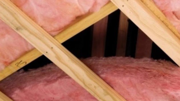 Pink fiberglass insulation installed between wooden attic rafters by ADDICT INSULATION, LLC in St. Charles, MO