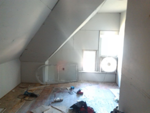 An attic room undergoing renovation with drywall installed and various tools on the floor, by Sanow Construction in Huron, SD.