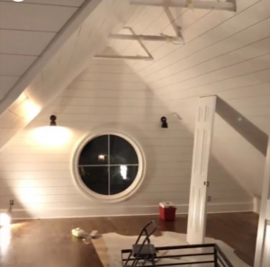 An attic space undergoing renovation with newly installed shiplap walls and a unique round window by Dogwood Renovation & Design, LLC in Kansas City, MO.