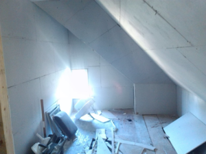 An attic room with new drywall being installed, showing ongoing renovation work by Sanow Construction in Huron, SD.