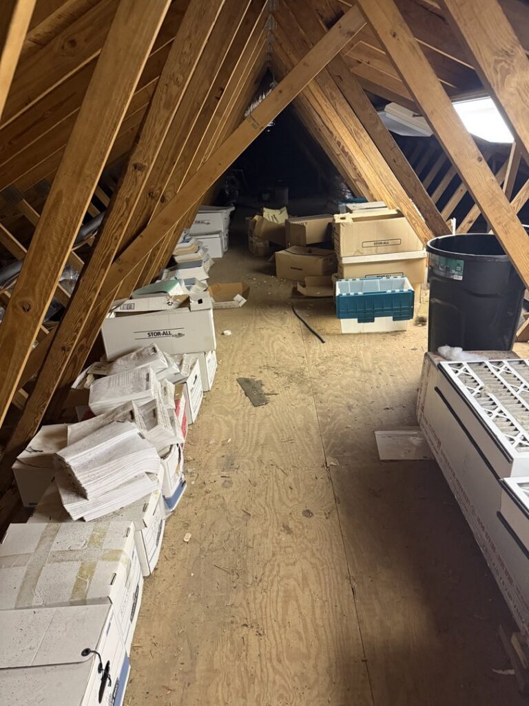 An attic space filled with numerous boxes and trash cans, indicating a junk removal job by LP Junk Removal in Birmingham, AL.