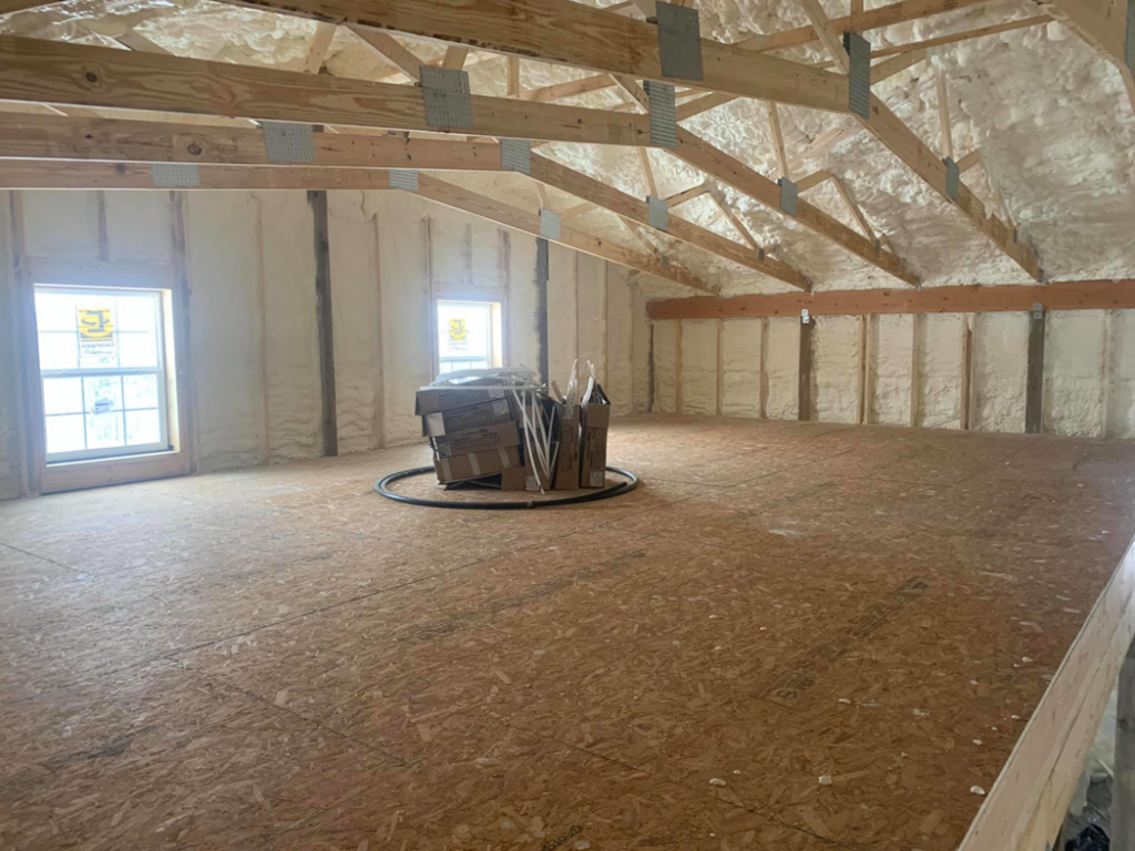 Spray foam insulation applied to roof rafters and walls in a residential attic by Spray Foam Solutions Of Erie in Erie, PA.