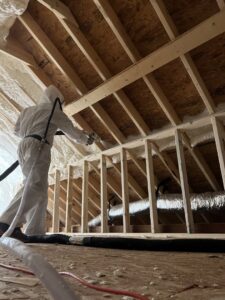 A worker applying spray foam insulation to the attic roof framing for Off-Axis Spray Foam and Radon Services in Clarksville, TN.