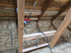 A robust attic winch system expertly installed among wooden beams by Hands On Repair in Renton, WA.