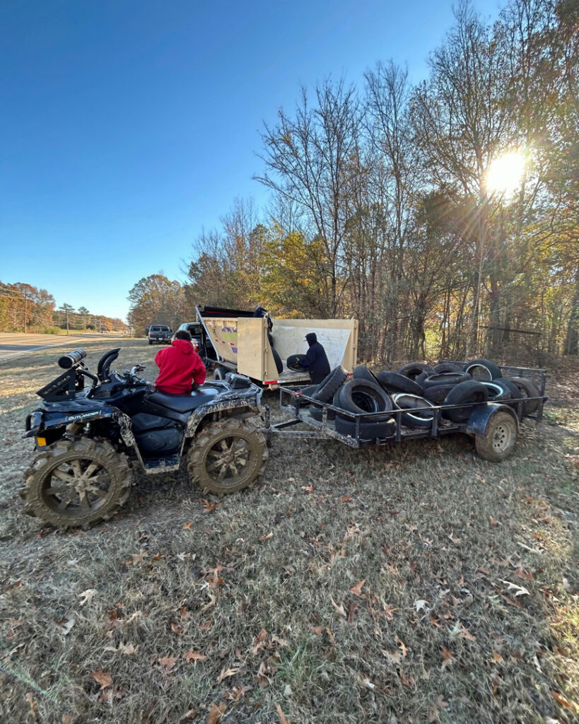 An ATV pulling a trailer full of old tires towards a dumpster for junk removal by Curry Dumpster Rentals LLC in Southaven, MS.