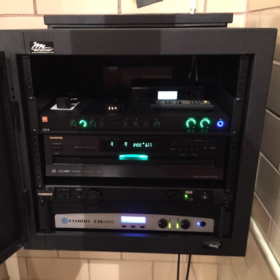 A professionally installed audio and video equipment rack by NU Current Electric Inc in New Ulm, MN, showcasing organized wiring.