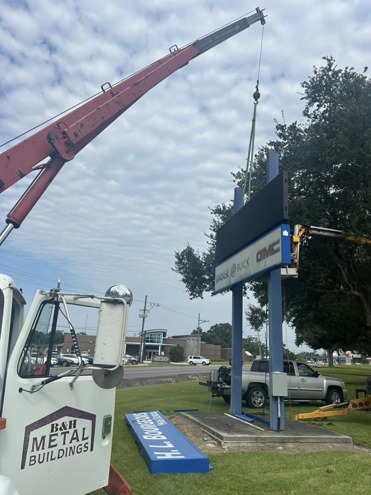 A B & H Metal Buildings Inc. crane truck lifting a sign component for installation in Kenner, LA.