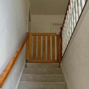 A wooden baby gate securely installed at the top of a staircase by Mr. Handyman of Northern Pittsburgh, PA.