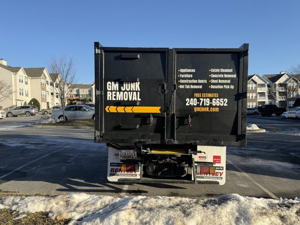 The back of a GM Junk Removal truck listing services and contact information in Frederick, MD.