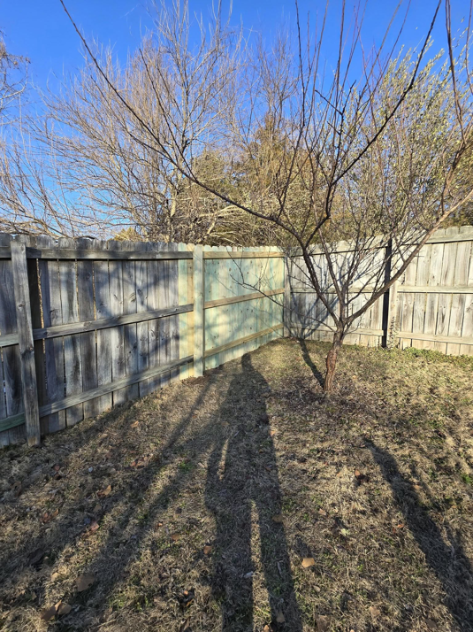 The back side of a wooden fence with a repaired section, showcasing fence work by Creekside Handyman NWA in Centerton, AR.