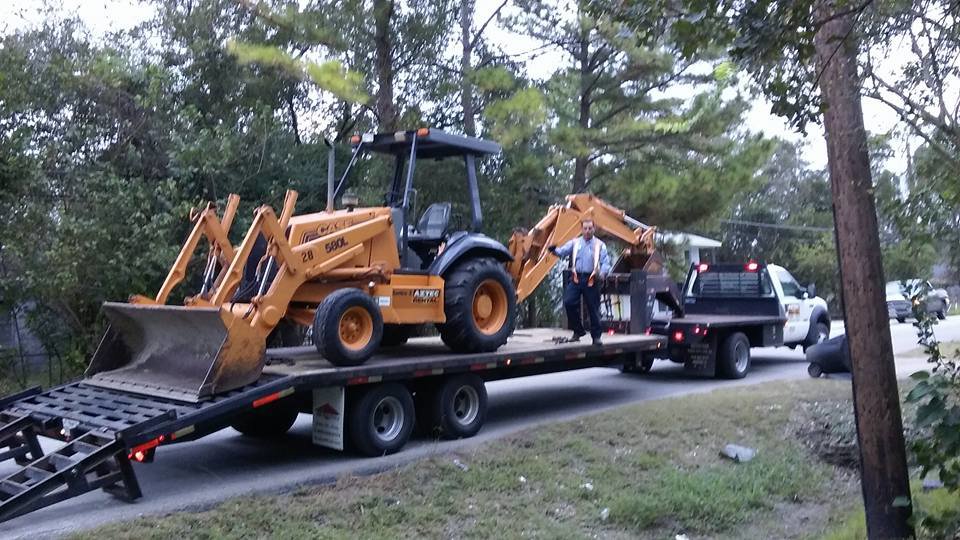 A backhoe loaded on a trailer for transport by All Aboard Contractors in Houston, TX.