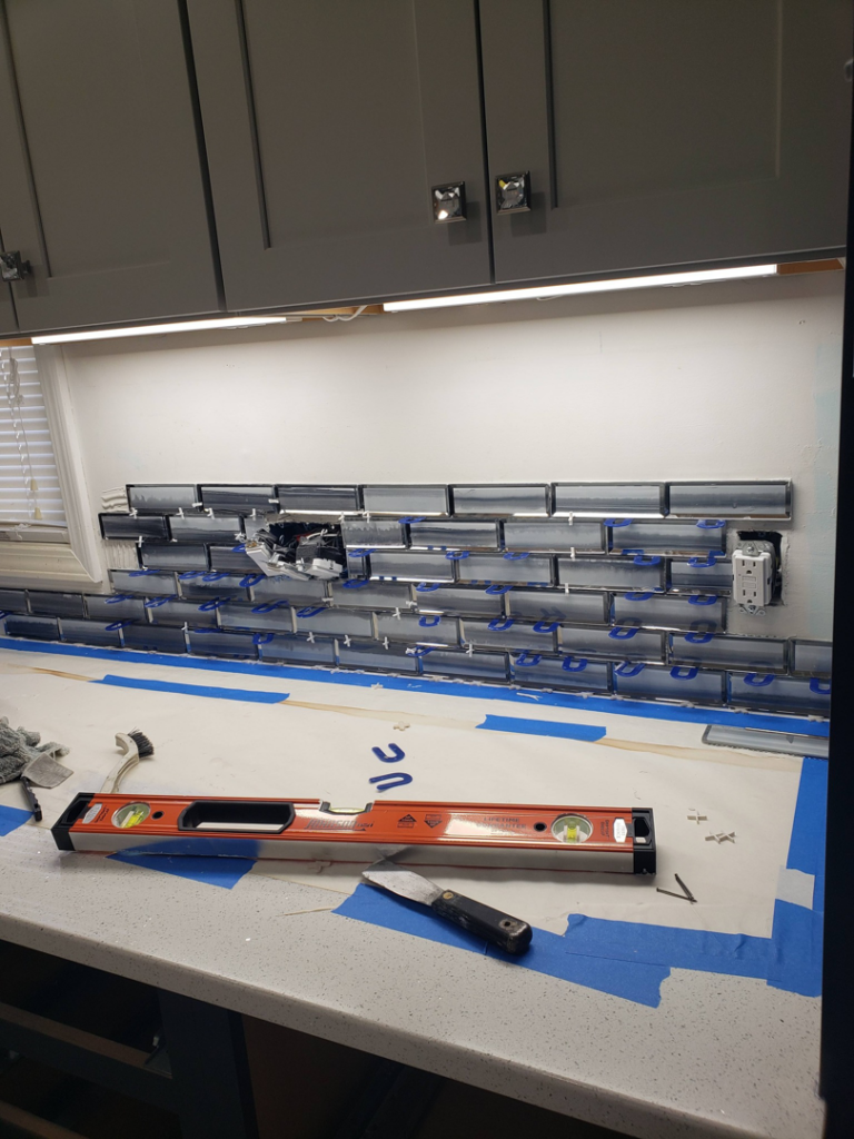 Backsplash tiling installation in progress with a level and tools by BEST QUALITY CONSTRUCTION COMPANY in Fountain Valley, CA.