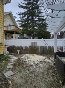A backyard showing sawdust and a cleared area after tree removal by Asg Tree Service in Kalamazoo, MI.
