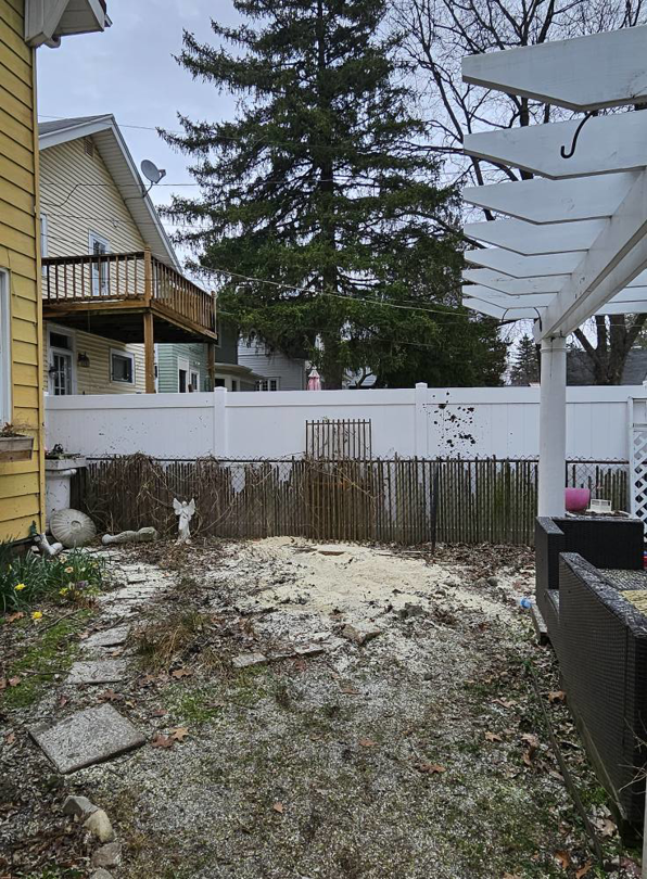 A backyard showing sawdust and a cleared area after tree removal by Asg Tree Service in Kalamazoo, MI.