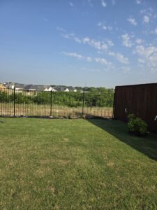 A new black metal fence defining a backyard space, installed by Tin Star Fencing in Fort Worth, TX