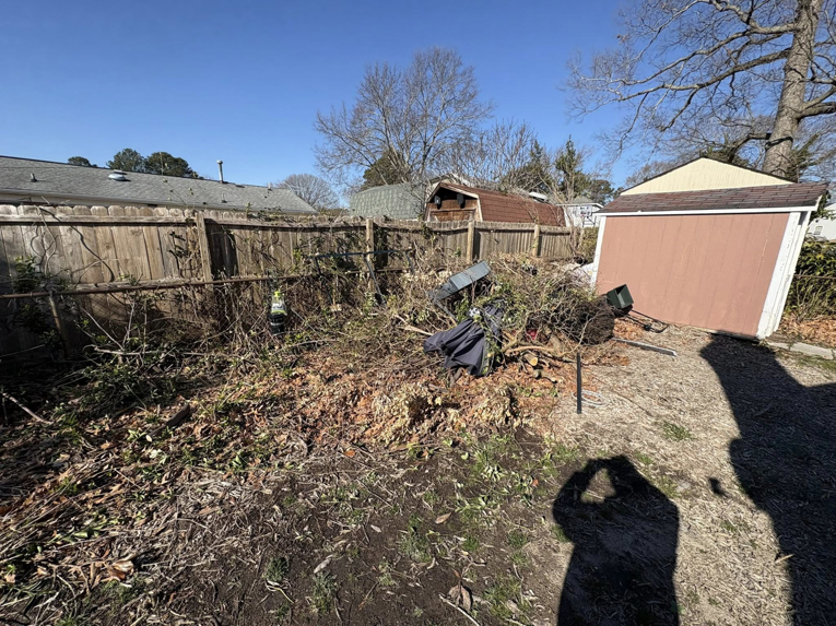 A large pile of brush, branches, and debris in a backyard ready for removal by EcoClear Junk Removal in Baltic, CT.