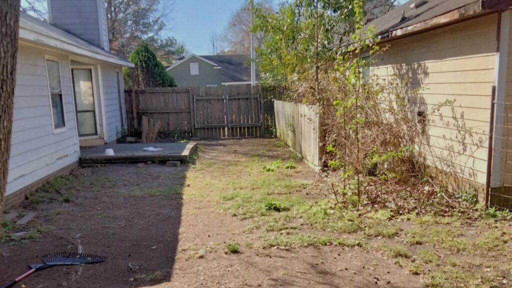 A backyard undergoing cleanup with a rake on the ground, handled by Mels Haul & Junk Removal in Raleigh, NC.