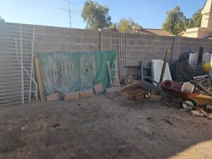A cluttered backyard with various items awaiting junk removal by Skunky's Junk Removal in Tempe, AZ.