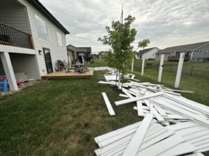A backyard with a pile of white wooden planks and construction debris ready for removal by Vargas Junk Removal & Dumpster Rentals in Urbandale, IA.